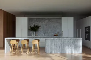 Modern minimalist kitchen featuring marble countertops and white cabinetry.