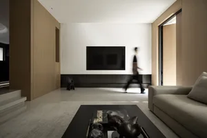 A modern minimalist living room with a large flat-screen TV mounted on the wall, a cozy sofa, and a coffee table with decorat
