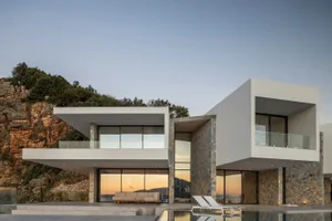 現代極簡住宅，石材立面搭配大型玻璃窗，俯瞰懸崖景觀