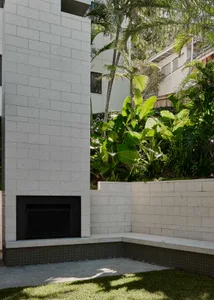 Outdoor fireplace made of cement with green foliage in the background, providing a cozy outdoor space.