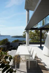 Modern patio featuring a wooden deck and metal frame furniture overlooking a scenic waterfront view.