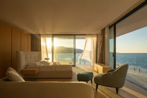 Modern residential interior featuring natural light and neutral tones, with a view of the ocean.