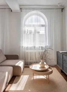 A minimalist living room with fabric furniture, wooden accents, and glass window treatments.