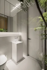 A modern minimalist bathroom with a concrete floor, minimalist white furniture, and a large mirror.