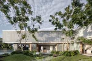 A contemporary exterior house with large glass windows and greenery surrounding it.