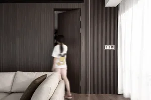 A modern interior design living room with wooden walls, a white sofa, and a woman walking through the doorway.