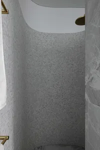 A modern marble shower with tiled walls and overhead rainfall shower head.