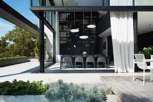 Modern residential dining area featuring gray furniture and concrete and glass elements.