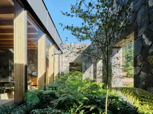 Modern residential architecture featuring glass, stone, and concrete materials.