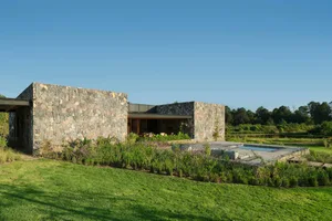 Modern residential home featuring stone exterior, glass walls, and wooden accents.