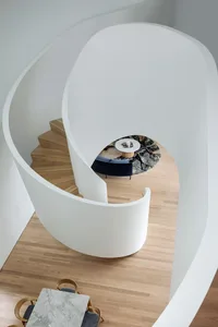 A modern staircase featuring a combination of wood and concrete materials and a curved, open-riser design.