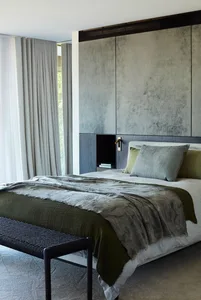 A minimalist bedroom featuring fabric bedding, a wooden bed frame, and a metal side table.