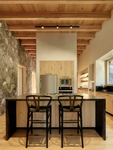 Minimalist kitchen with wooden island featuring modern appliances and seating.