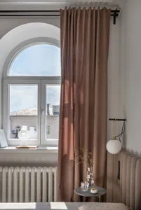 A modern bedroom featuring a brown textile curtain by the window