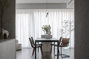 Modern minimalist dining room with white curtains, marble table, leather chairs, and indoor plants.