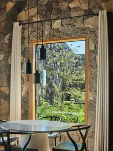 Modern dining room interior with wooden furniture, glass pendant lights, and stone walls