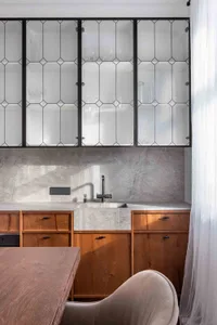 Modern kitchen featuring wood cabinets, concrete countertops, and glass cabinets.