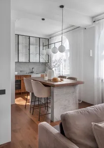 A modern kitchen featuring a concrete kitchen island with a wooden countertop and a minimalist design.