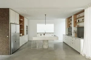 A modern minimalist kitchen with a concrete countertop, stainless steel appliances, and white cabinetry.