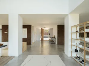 Modern living room with concrete flooring, wooden furniture, and textured cork walls.