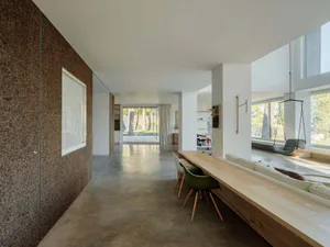 A spacious, modern residential interior featuring minimalist design, concrete flooring, and ample natural light, with a minim