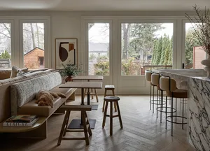 A modern living room featuring a cozy, bohemian-designed couch against a white wall, with wooden stools and a table.