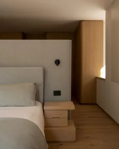 Modern minimalist bedroom featuring a upholstered bed with a fabric headboard and wooden bedside tables.