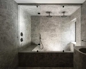 Modern minimalist bathroom with marble finishes, featuring a glass-enclosed shower and sleek black fixtures.
