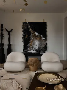 Interior design featuring white upholstered chairs, abstract art, and mixed-media decor.