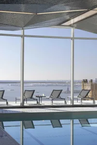 An indoor swimming pool with lounge chairs and a view of the Statue of Liberty.