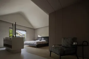 Modern minimalist bedroom featuring a black leather bed, wooden flooring, and a glass partition wall.