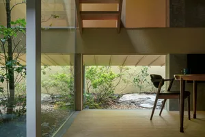 Modern minimalist residential space featuring glass walls and wooden furniture.