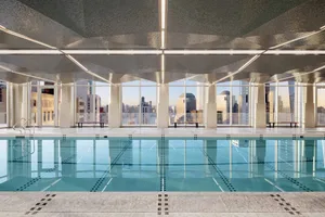 A modern indoor swimming pool with a glass wall overlooking the city.