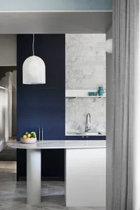 A modern kitchen with a marble countertop and navy blue cabinets.