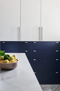 A modern minimalist kitchen with marble countertops and blue textured cabinets.