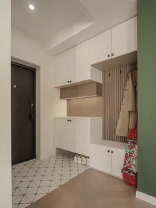 A modern entryway featuring white cabinets with wooden accents and built-in shoe storage beneath