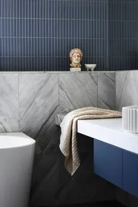 Modern bathroom featuring a freestanding bathtub, marble countertop, and a statue on the shelf.
