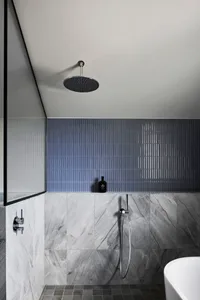 Modern minimalist bathroom featuring marble tiles, a walk-in shower, and a freestanding bathtub.