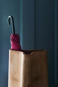 A red umbrella in a modern large ceramic umbrella stand