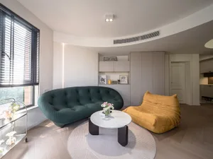 A modern living room with a green and yellow terrazzo couch, a round coffee table, and a round rug.