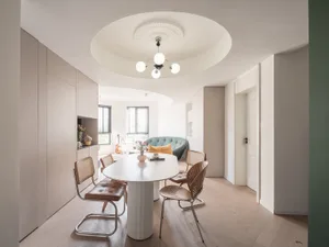 A modern living room with white walls, a white table, and brown chairs.