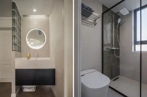 Modern minimalist bathroom with a sleek sink, large round mirror, and dark wooden vanity. The shower area features a glass en