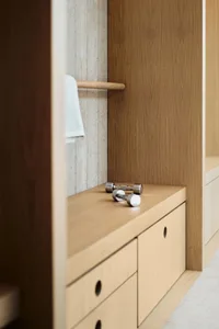 Closeup of a minimalist closet with wooden cabinets and a towel hanging on the rack.