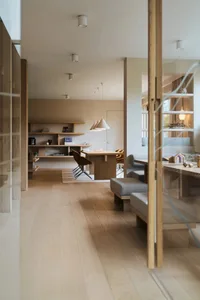 Modern living room with a wooden floor, chairs, and shelves.