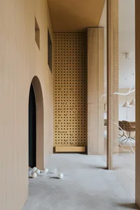 A modern playroom with wooden walls and a carpeted floor, featuring a ball pit and an archway leading to another room.