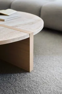 A minimalist interior design featuring a natural stone table with a wooden frame and books.