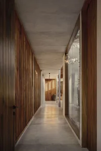 A modern residential hallway featuring wooden-paneled walls and a concrete floor