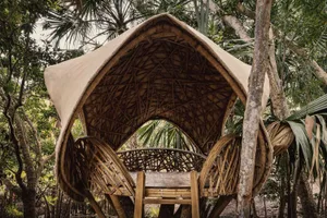 A shelter made of natural bamboo surrounded by greenery.