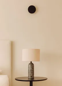 A minimalist bedside lamp with a marble base and fabric shade, placed on a small round table.