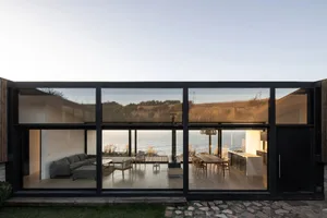 Modern minimalist residential patio enclosed with glass walls overlooking the ocean.